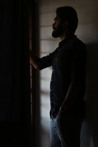 Side view of young man looking through window