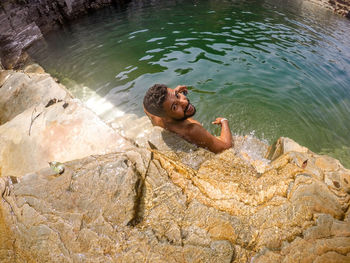 High angle view of shirtless man on rock in lake