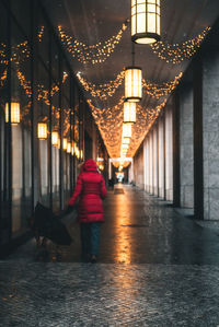 Rear view of woman walking in illuminated corridor