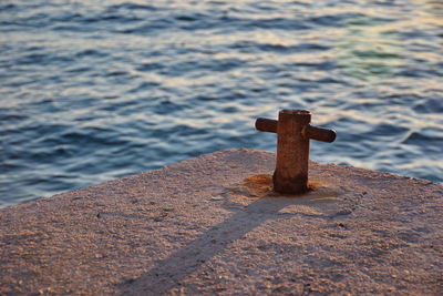 Closup of concrete dock with metal wedge against the blue sea in sunset