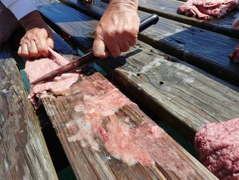 Close-up of butcher cutting meat on wood