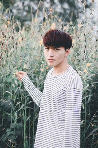 Portrait of young man standing by plants at park