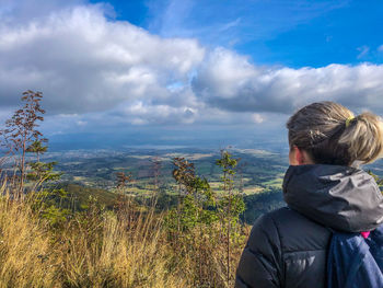 Rear view of people looking at mountain against sky