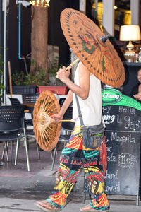 Midsection of woman holding umbrella standing on street in city