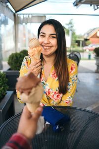 Portrait of smiling woman holding ice cream outdoors