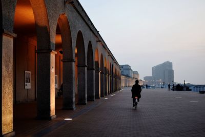 Woman walking in city against sky