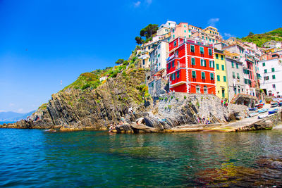 Scenic view of sea by buildings against blue sky