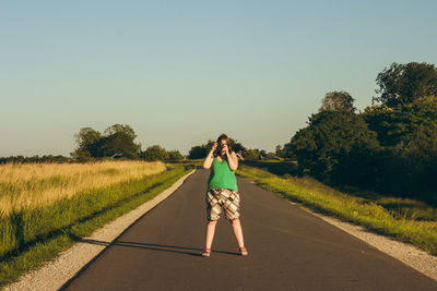 Rear view of woman on road against clear sky