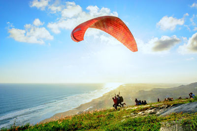 People paragliding at beach against sky