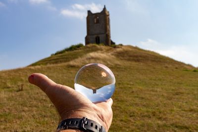 Person holding lensball against church on hill