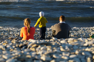 Rear view of person standing on rocks at beach