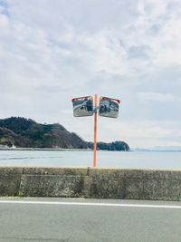 Road sign by street against sky