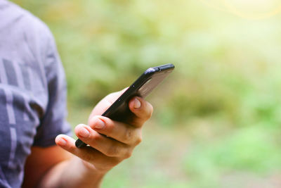 Midsection of person using mobile phone outdoors