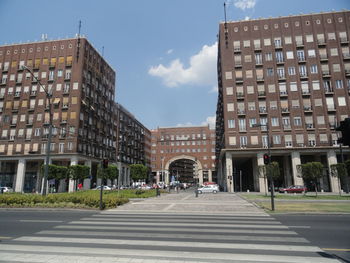 Road by buildings against sky