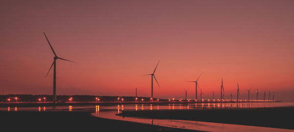 Silhouette of wind turbine against sky during sunset