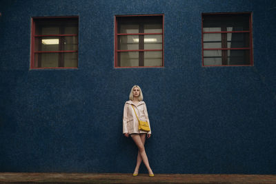 Portrait of woman standing against wall