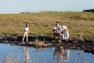 Rear view of people standing in water against sky