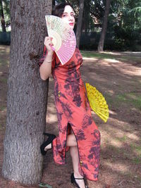 Portrait of woman standing by tree trunk