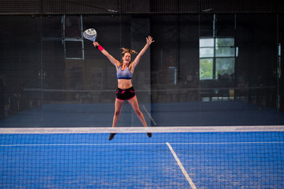 Portrait of beautiful young wimmer girl exulting on indoor padel tennis court