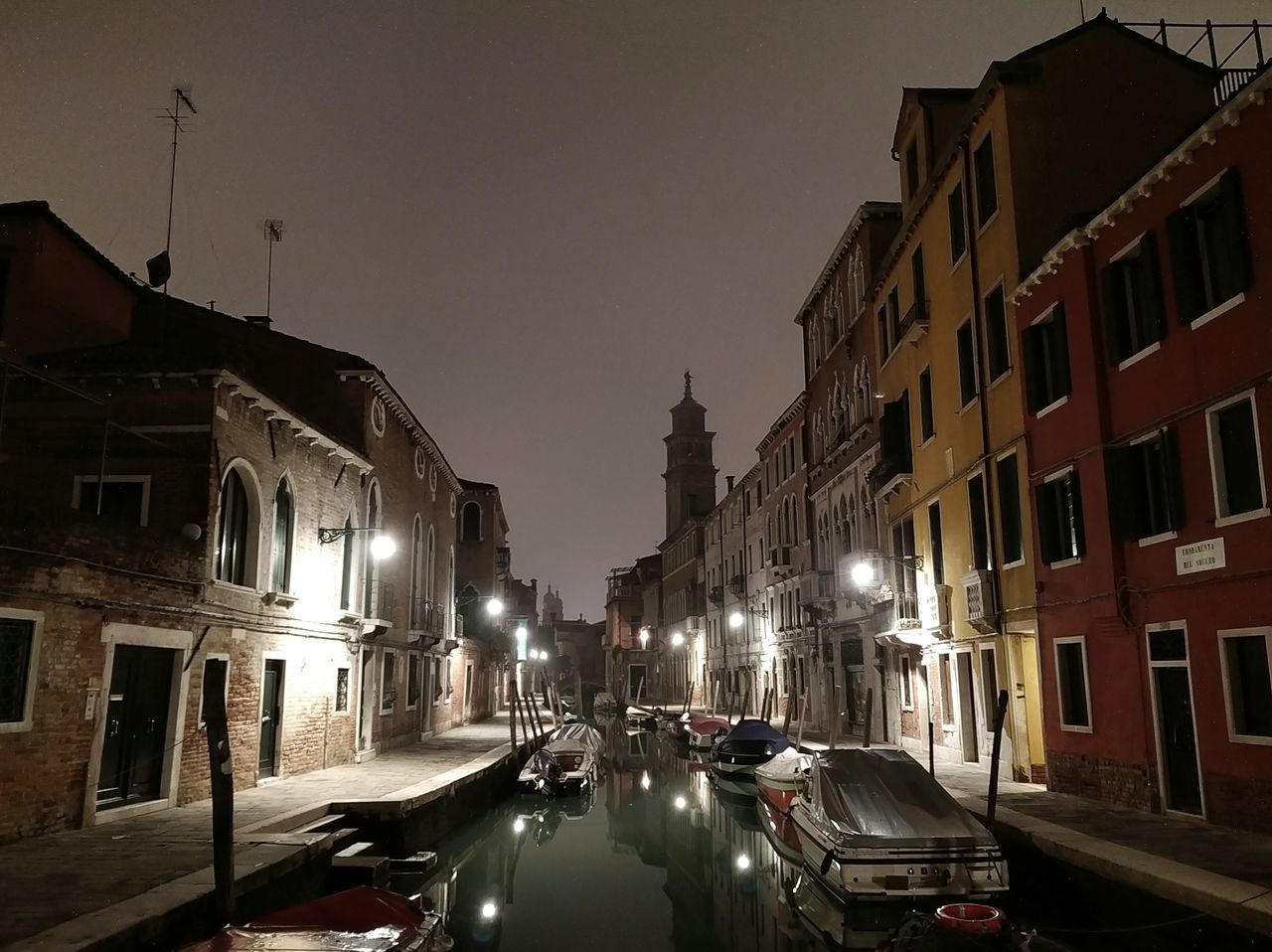 CARS ON ROAD AMIDST BUILDINGS AGAINST SKY AT NIGHT