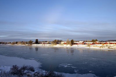 Buildings by trees against sky during winter