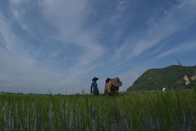 Rear view of people on field against sky