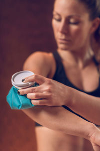 Close-up of woman holding ice pack on elbow