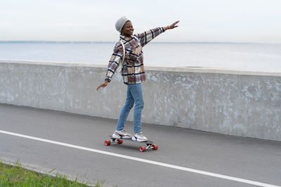 Freedom and urban lifestyle. young girl skateboarding on longboard at city road or deck near sea