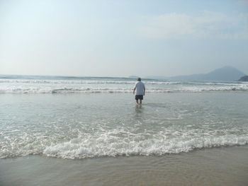 Rear view of man on beach against sky