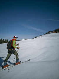 Man skiing on snowy mountain against sky