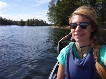 Portrait of smiling young woman in lake against sky