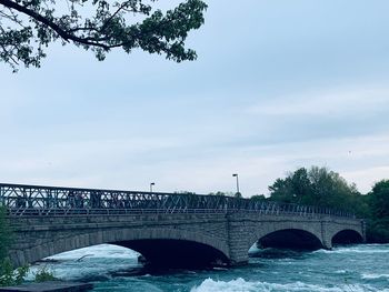 Arch bridge over river against sky