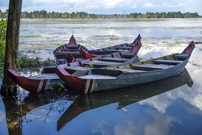 Boat moored on lake against sky