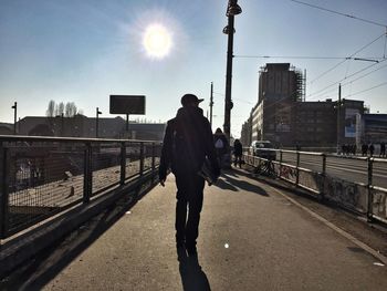 Man standing on railing in city against sky