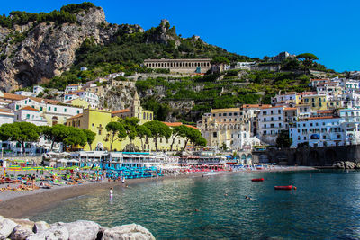 View of the beach with its bathers from the town of amalfi with the sea, boats and houses