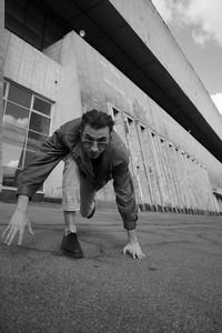 Full length of man sitting on bridge in city