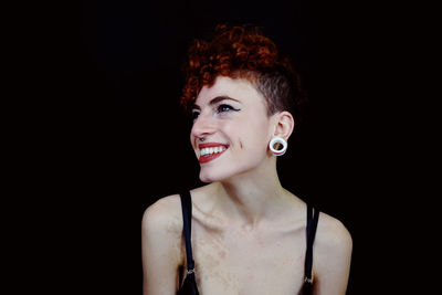 Portrait of smiling young woman against black background