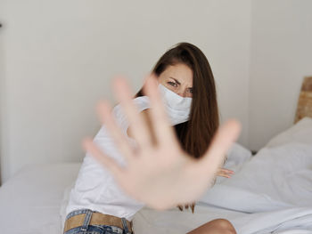 Portrait of young woman sitting on bed at home