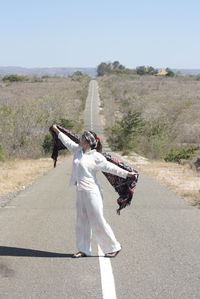 Rear view of woman walking on road against sky