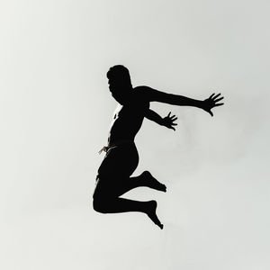 Low angle view of silhouette man jumping against clear sky