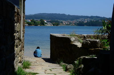 Rear view of woman by sea against clear blue sky