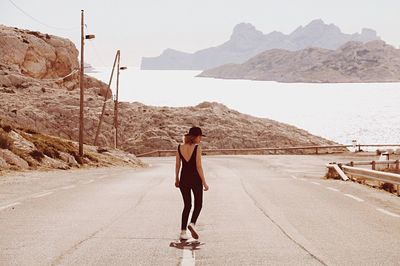 Rear view of woman standing on road