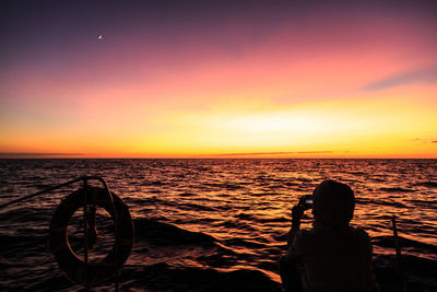 Rear view of woman on boat against sea during sunset