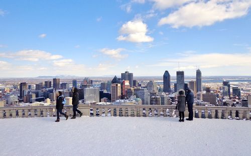 People on modern buildings in city against sky