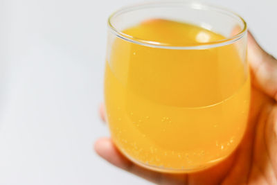 Close-up of hand holding drink against white background