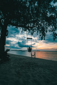 Silhouette person on beach against sky during sunset