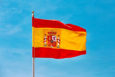 Low angle view of flag waving against blue sky