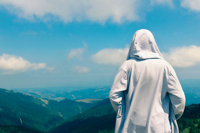 Rear view of man enjoying the view on mountains against the sky. copy space.