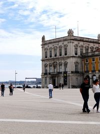 People walking in city against clear sky