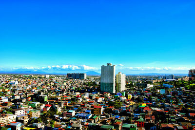 Aerial view of modern buildings in city against blue sky